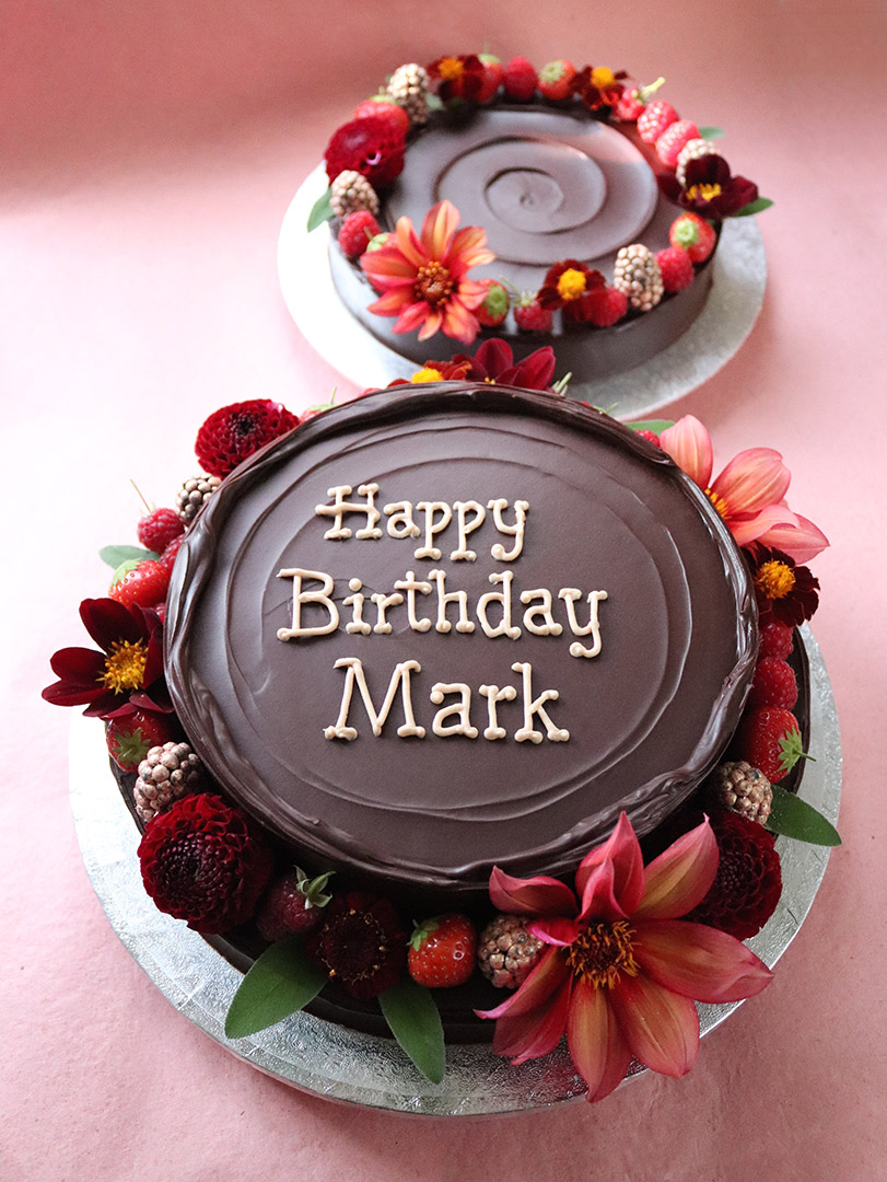 The perfect centrepiece for a special birthday. Two Reines de Saba – chocolate & almond cakes with rum. All ingredients gluten-free. Covered with dark ganache and decorated with berries and organic edible flowers