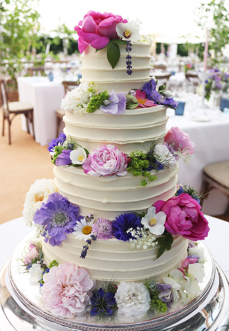 The perfect centrepiece for your glutenfree wedding: a four-tier white wedding cake for a summer wedding in the Hampshire countryside. Three flavours: Carrot Cake, Lemon & Elderflower and White Chocolate & Raspberry. All ingredients gluten-free. Decorated with unsprayed, sustainably-grown flowers, grown locally by Hortus Poeticus