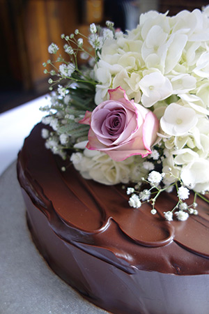 Award winning gluten-free rich chocolate cake for a wedding. Made with organic ground almonds, dark chocolate and Jamaica rum. Covered with dark chocolate ganache and decorated with fresh flowers. All ingredients gluten free