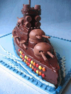 Chocolate Battleship Cake, made with organic gluten-free chocolate sponge. Filled with chocolate buttercream and frosted with dark chocolate ganache. Decorated with glutenfree chocolate beans, sweets and biscuits. Delivered to Wimbledon, London