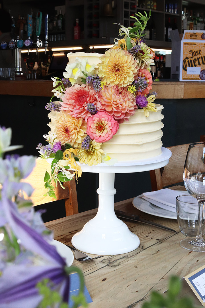A gluten free October wedding cake at The Lordship Pub. Two tiers of Vanilla & Raspberry cake. All ingredients glutenfree. Decorated with organic edible flowers from Blooming Green and the Bee Urban garden. Price includes delivery and assembly at your London venue