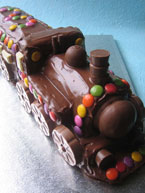 Chocolate Train Cake, made with organic gluten free chocolate sponge and decorated with chocolate beans and biscuits. Delivered to Kennington, London